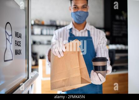 Waiter preparing a take away order, looking at camera. Coronavirus concept. Stock Photo