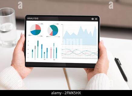 Unrecognizable woman using financial app for stocks and markets analysis on digital tablet at home, creative image. Cropped of lady analysing financia Stock Photo