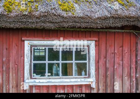 Old bottles in a window on red cottage Stock Photo