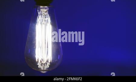 Vintage Edison light bulb reproduction on blue background. Stock Photo