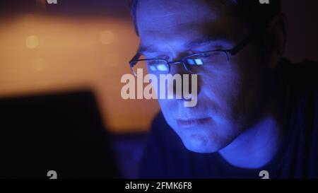 Man in glasses with laptop pc in the evening at home. Stock Photo