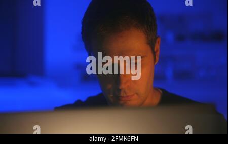 Man in glasses with laptop pc in the evening at home. Stock Photo
