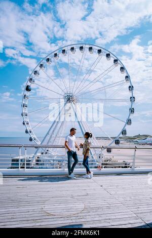 The Ferris Wheel The Pier at Scheveningen, The Hague, The Netherlands on a Spring day, couple man and woman mid age on the beach Stock Photo