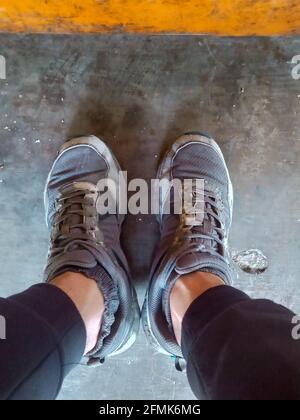 a color photo of a pair of feet wearing worn shoes in the morning Stock Photo