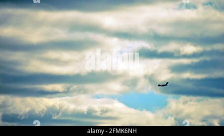 Airplane flying in dark cloudy sky Stock Photo