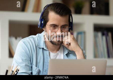 Close up focused man in glasses and headphones using laptop Stock Photo