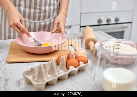 Woman beats eggs in a bowl. housewife cooking on kitchen Stock Photo