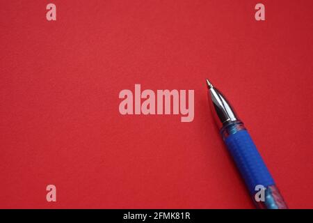 Blue ballpoint pen on red paper, copy space Stock Photo