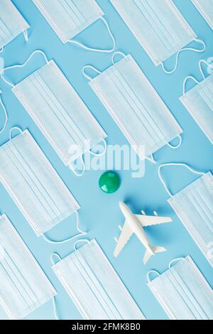 A white plane surrounded by protective masks on a blue background with a green and red dot as the destination. The concept of allowing and banning air Stock Photo