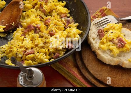 scrambled eggs and bacon in pan with bread Stock Photo