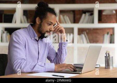 Focused thoughtful African American businessman looking at laptop screen Stock Photo