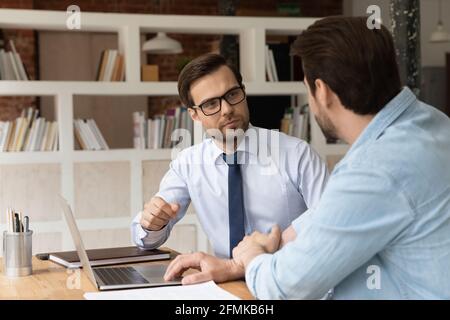 Two colleagues coworkers working on project together, discussing strategy Stock Photo