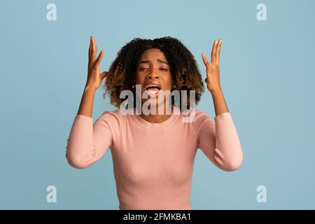 Why Me. Desperate Black Woman Complaining About Something Over Blue Background, Unhappy Stressed Emotional African American Female Mourning, Depressed Stock Photo