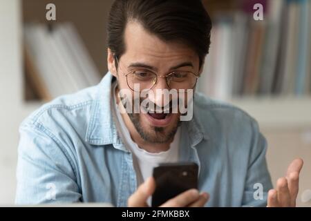 Close up surprised man in glasses looking at phone screen Stock Photo