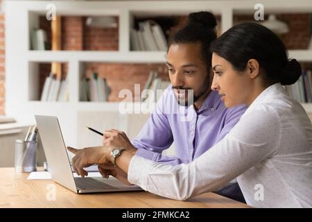 Close up confident Indian businesswoman mentor teaching African American intern Stock Photo