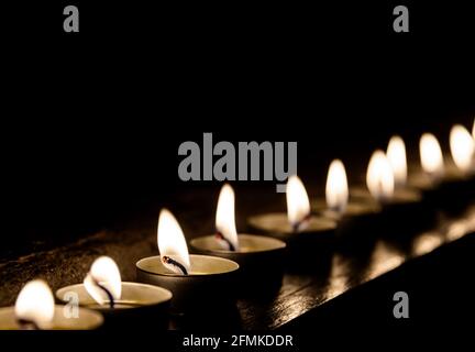 Lit candles in a row at night Stock Photo