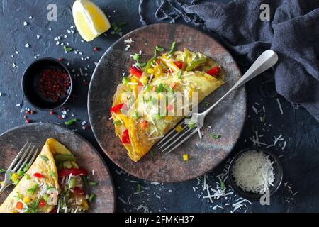 Healthy breakfast food: stuffed omelette with vegetables on dark background. Top view with copy space. Stock Photo