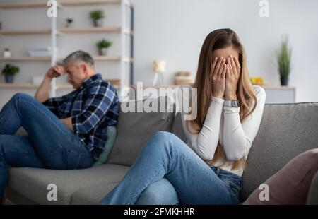 Upset mature woman crying on sofa after fight with her husband at home, copy space. Middle-aged family suffering from marital crisis and having relati Stock Photo