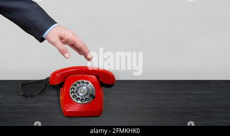 hand holding a red phone on wooden table Stock Photo