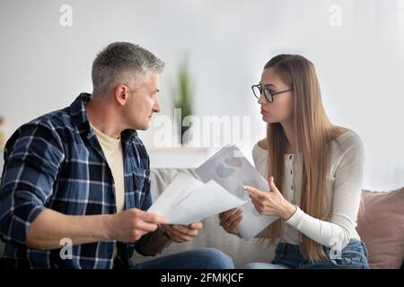 Family budget management. Focused mature couple difcussing financial issues, holding documents at home. Senior man and his wife checking taxes or insu Stock Photo