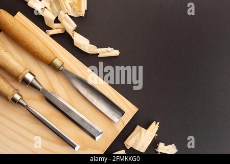 Set of gauges and chisel on wooden plank on black background. Woodworking or carpentry flat lay. Top view. Copy space Stock Photo