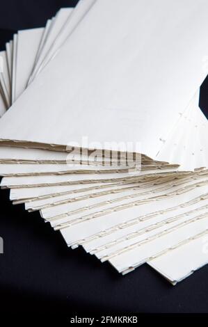 The process of book binding; pile of raw paper folders. Black background Stock Photo