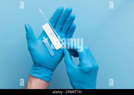 Doctor in blue gloves using a lateral flow covid-19 testing kit Stock Photo