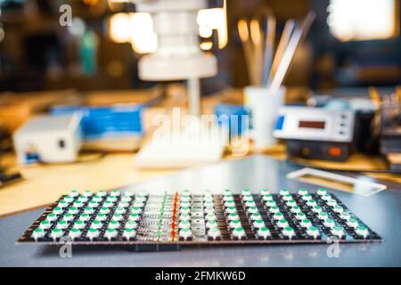 Large electron microscope and panel of LED light indicators are stacked on plate to prepare for the research of electronic components in a laboratory Stock Photo