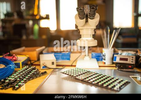 Large electron microscope and panel of LED light indicators are stacked on plate to prepare for the research of electronic components in a laboratory Stock Photo