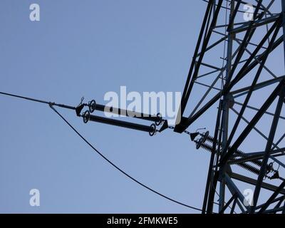 Metallic towers supporting the copper cables that carry electric power; towers over the blue sky: High voltage towers, engineering work to support the Stock Photo