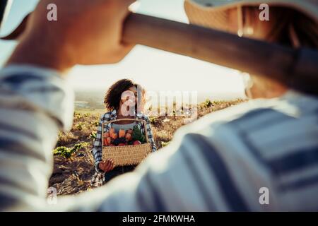 Farm workers chatting and smiling standing on farmland with fresh produce Stock Photo