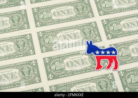 Democrat donkey logo patch badge & US $1 dollar banknotes. For US political fundraising & DNC Democrat campaign funds, Biden debt pile, small $ donors Stock Photo