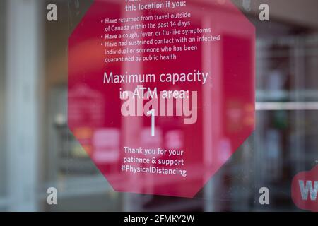 View of sign on the window Maximum capacity in ATM area 1 person due to Covid-19 in Courtenay, Canada Stock Photo