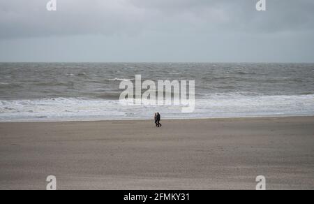 Panorama view of elderly couple walking along sand beach near Westkapelle Domburg Veere Zeeland Netherlands North Sea Europe Stock Photo