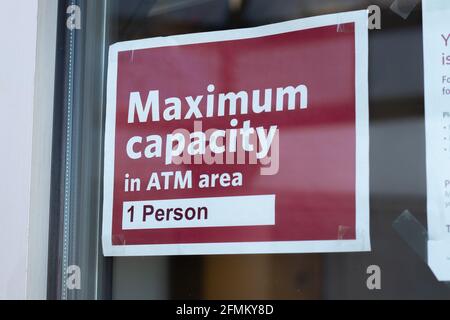 View  of sign on the window Maximum capacity in ATM area 1 person due to Covid-19 Stock Photo