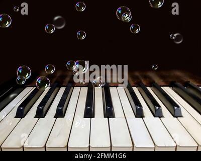 floating iridescent bubbles on old piano keys Stock Photo