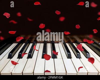 falling red rose petals on grungy old piano keys Stock Photo