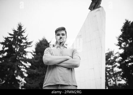 Grayscale shot of a young Caucasian male with crossed arms Stock Photo