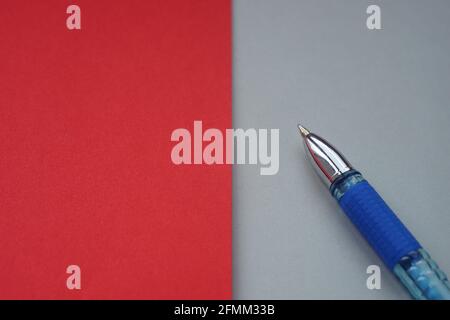 Blue ballpoint pen on grey with red paper, copy space on red side Stock Photo