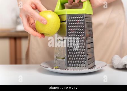Cook is grating an apple. Preparing baking ingredients. Stock Photo
