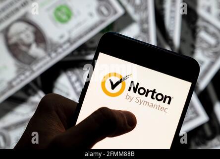 In this photo illustration the cybersecurity and anti-virus malware software developed by Symantec Corporation, Norton Anti-virus logo seen displayed on a smartphone with USD (United States dollar) currency in the background. Stock Photo