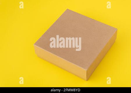 Square cardboard box on yellow background. Copy space. Mock up Stock Photo