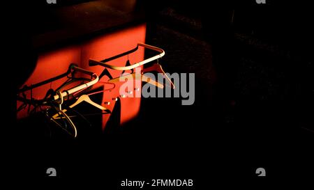 Empty hangers in sunlight with red and black backgrounds. Abstract and color image. Stock Photo