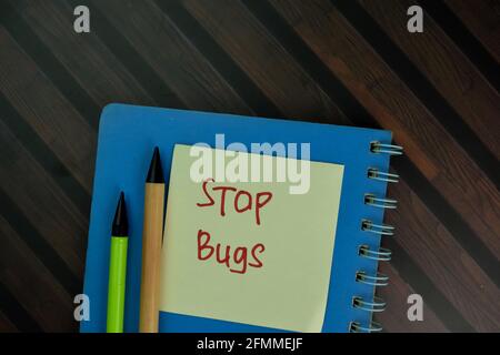 Stop Bugs write on sticky notes isolated on Wooden Table. Stock Photo