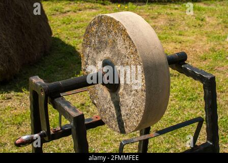Old grinding sharpening whetstone manual wheel in rural house garden closeup Stock Photo