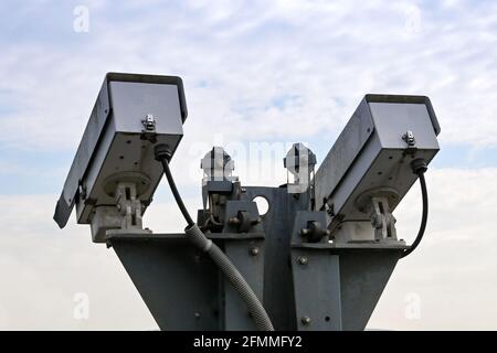Pair of remote controlled CCTV video cameras isolated against a clear sky. No people. Stock Photo