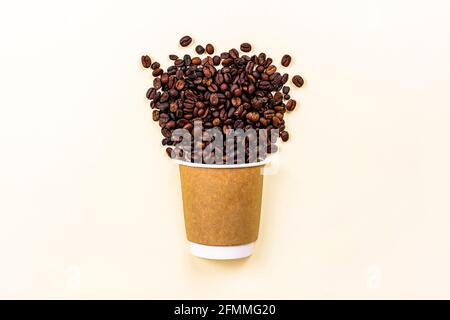 Brown cardboard disposable cup with coffee and roasted coffee beans with copy space on light background. Takeaway food concept. Stock Photo