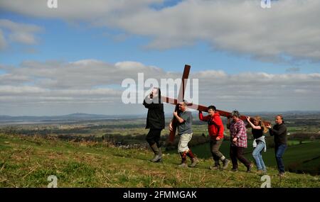 Carrying a wooden cross up Cam Peak on Good Friday before Easter Sunday in a walk of witness, Gloucestershire Stock Photo