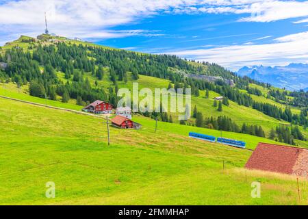 Scenic landscape between Alps, valleys of Rigi Mountain railways and blue cog train. Rigi Kulm summit and telecommunications tower on background Stock Photo