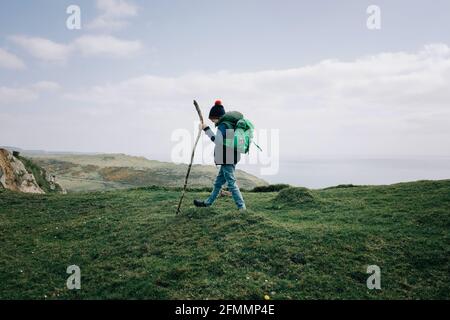 boy hiking along the Jurassic coast with a walking stick exploring Stock Photo